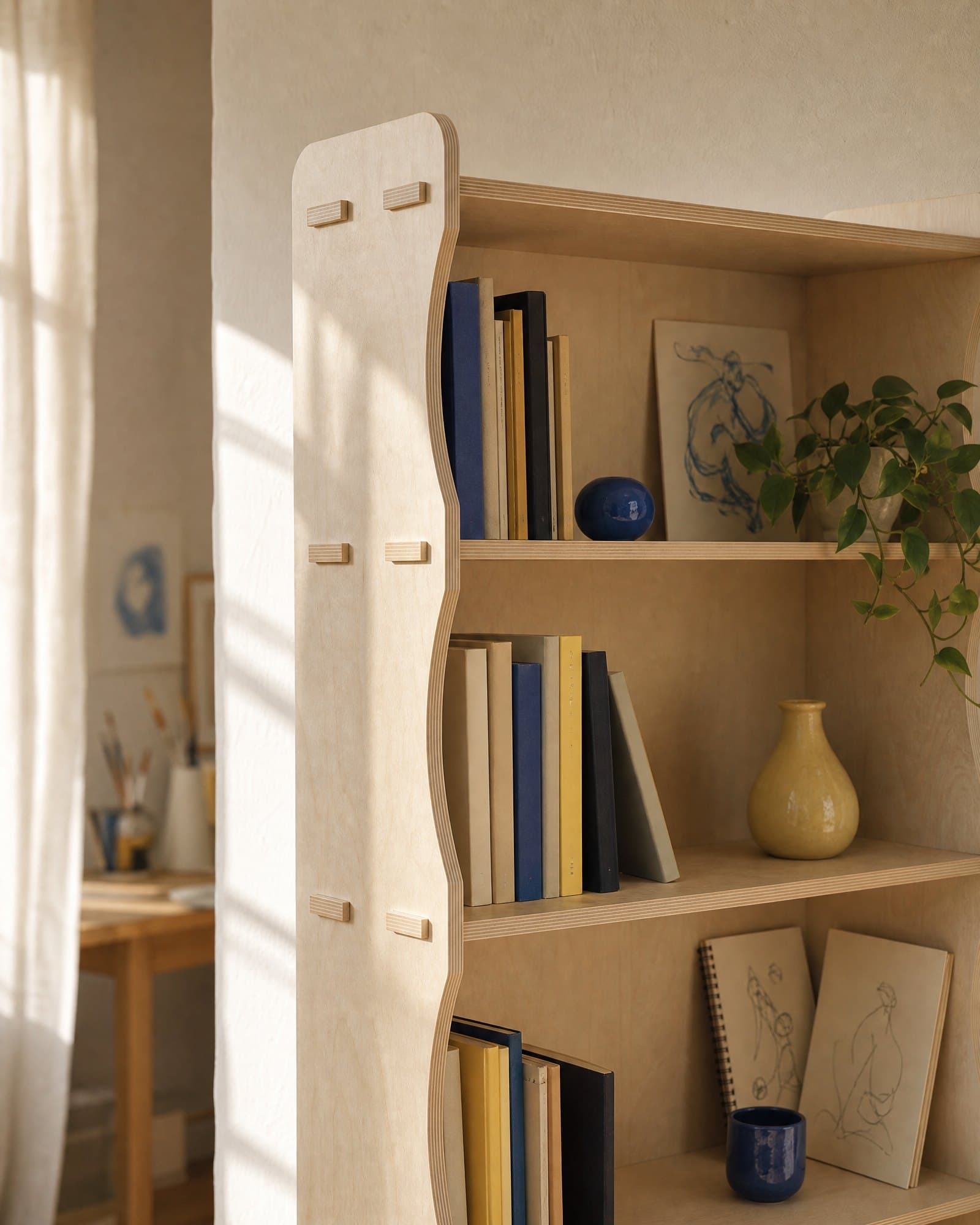 Image générée par IA : le haut de la bibliothèque Bübliondul, de trois quarts, contre un mur crème au soleil de fin d'après-midi, garnie de livres bleus et jaunes